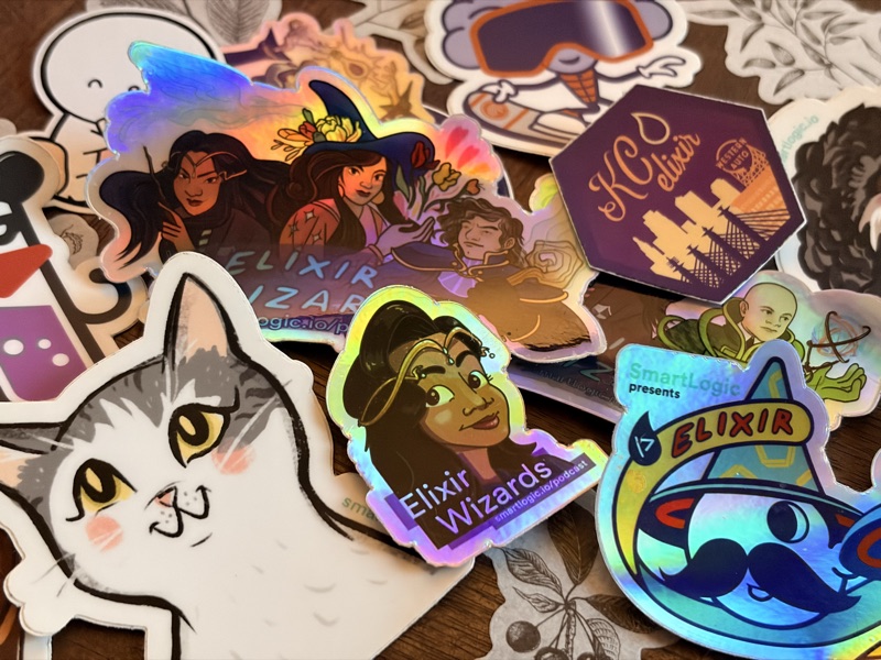 A pile of Elixir community stickers, including Elixir Wizards podcast stickers